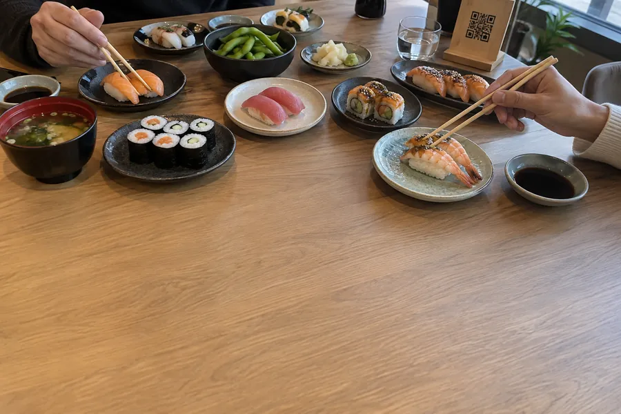 A table of an all-you-can-eat sushi restaurant, covered with small plates of sushi and maki